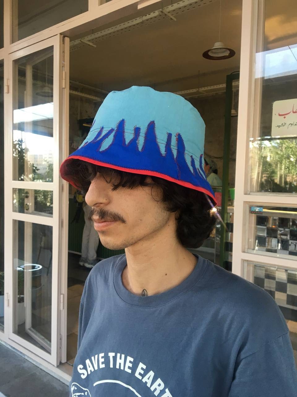 Model wearing a sky-blue bucket hat with dark blue drip applique