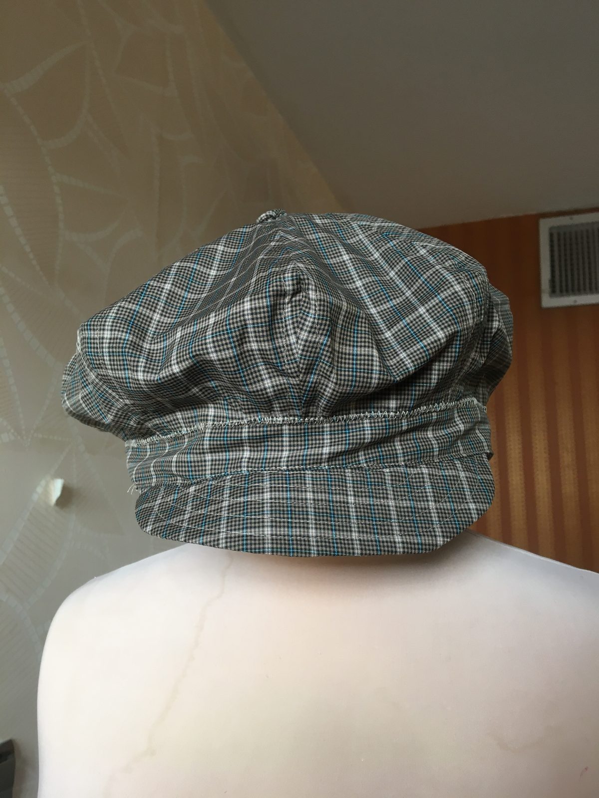 Grey plaid flat cap photographed on a white background