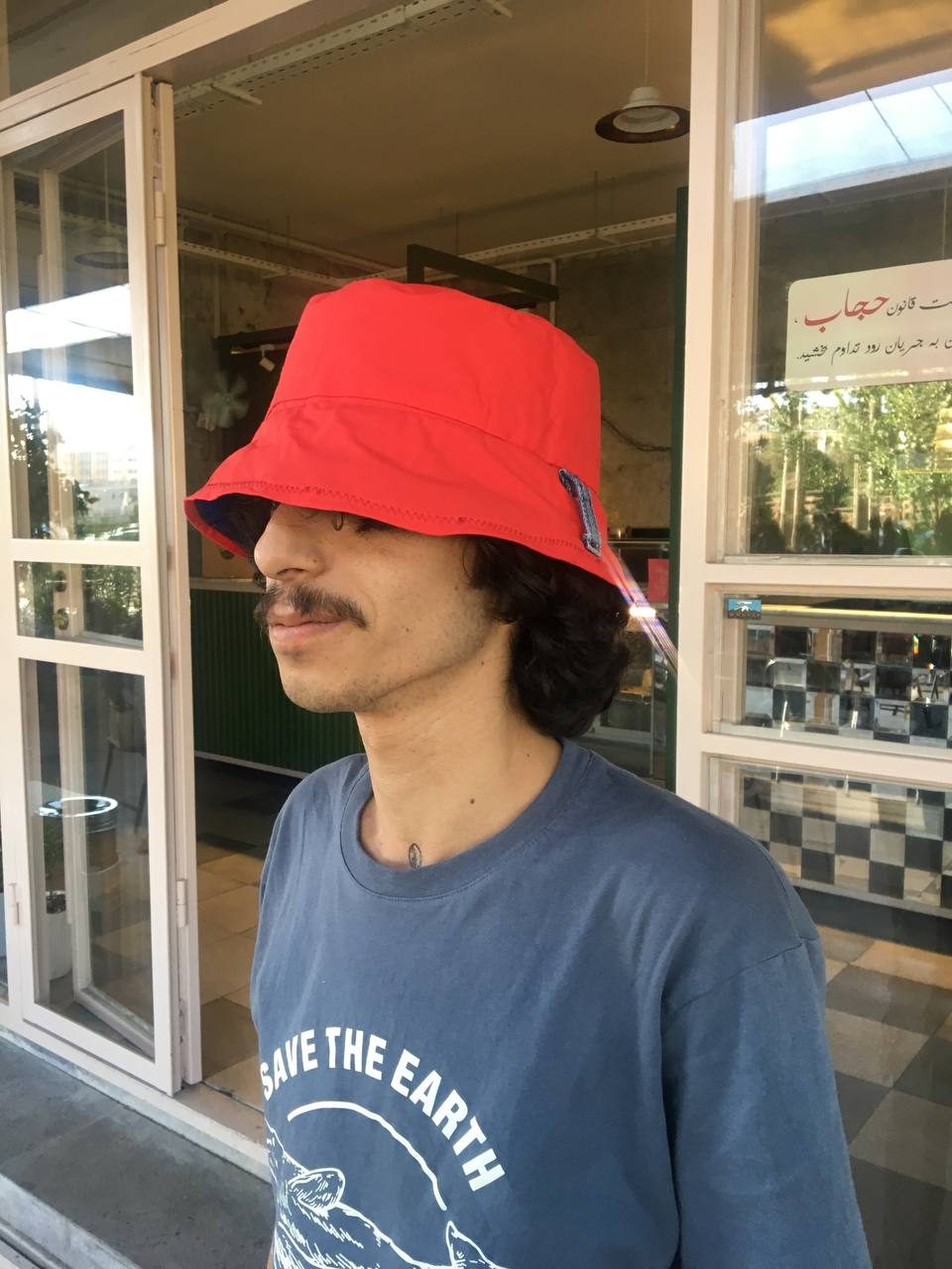 Model wearing a bright red bucket hat, seen from the side