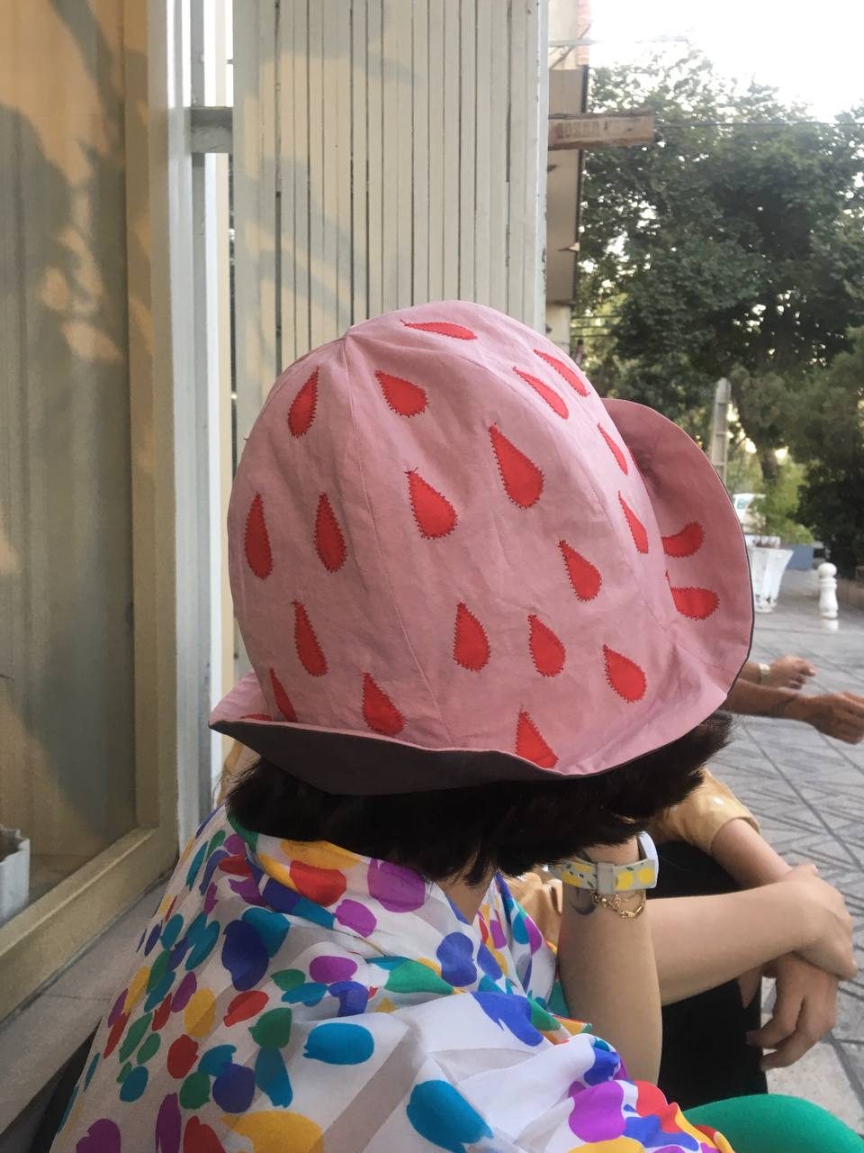 Model at a sunny window wearing a pink strawberry bucket hat
