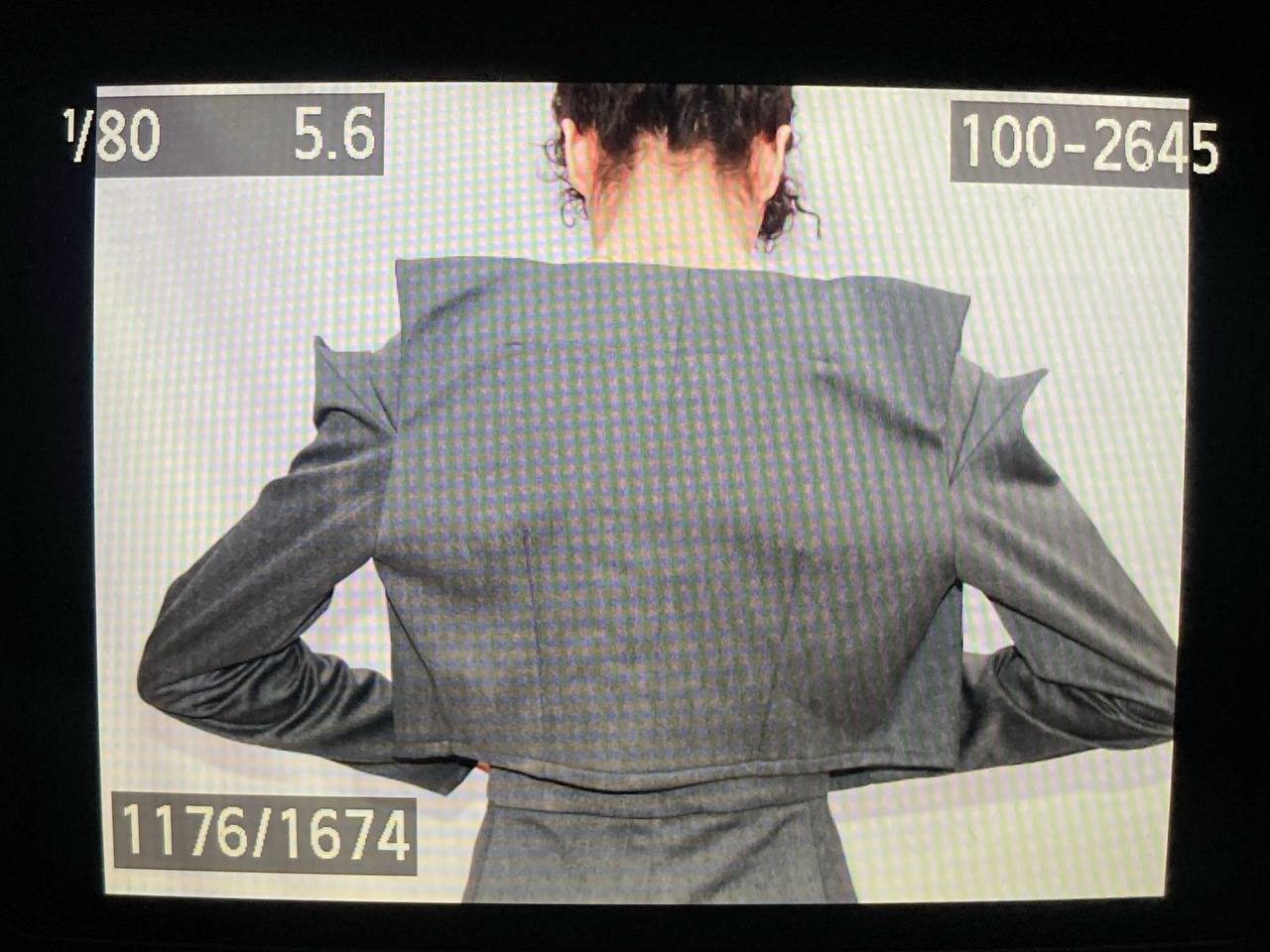 Back view of a tailored grey jacket with angular shoulder seams