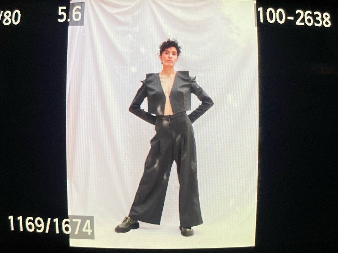 Model in a structured grey jacket with sculpted shoulders and wide trousers
