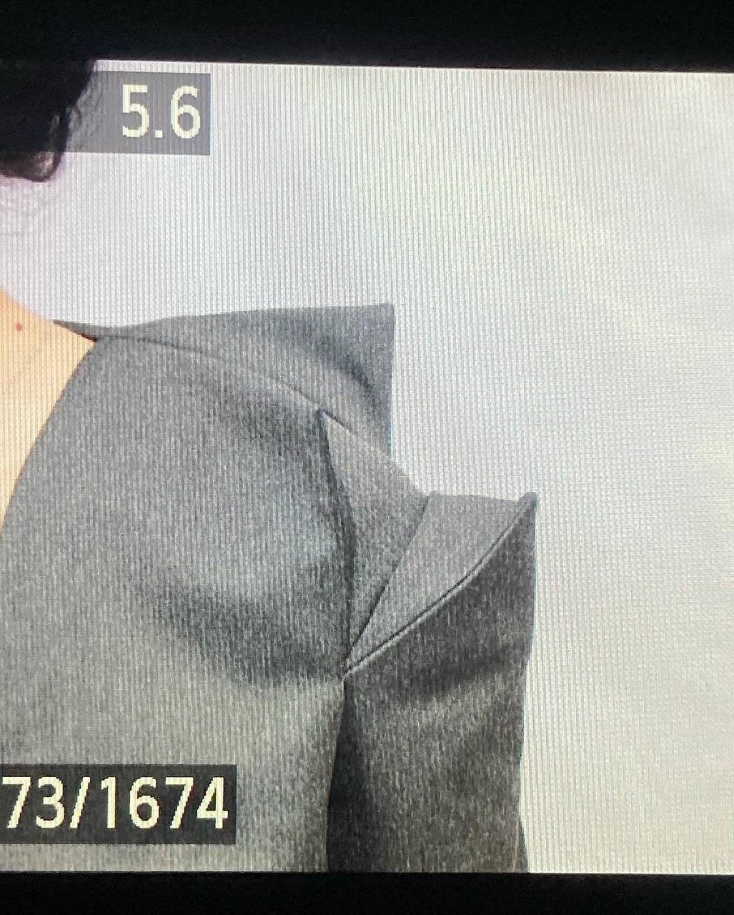 Close-up of the folded shoulder construction of a grey jacket