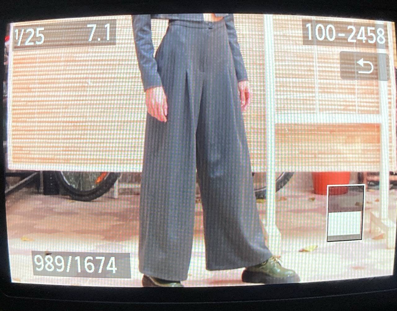 Wide-leg grey trousers worn in front of a workshop window