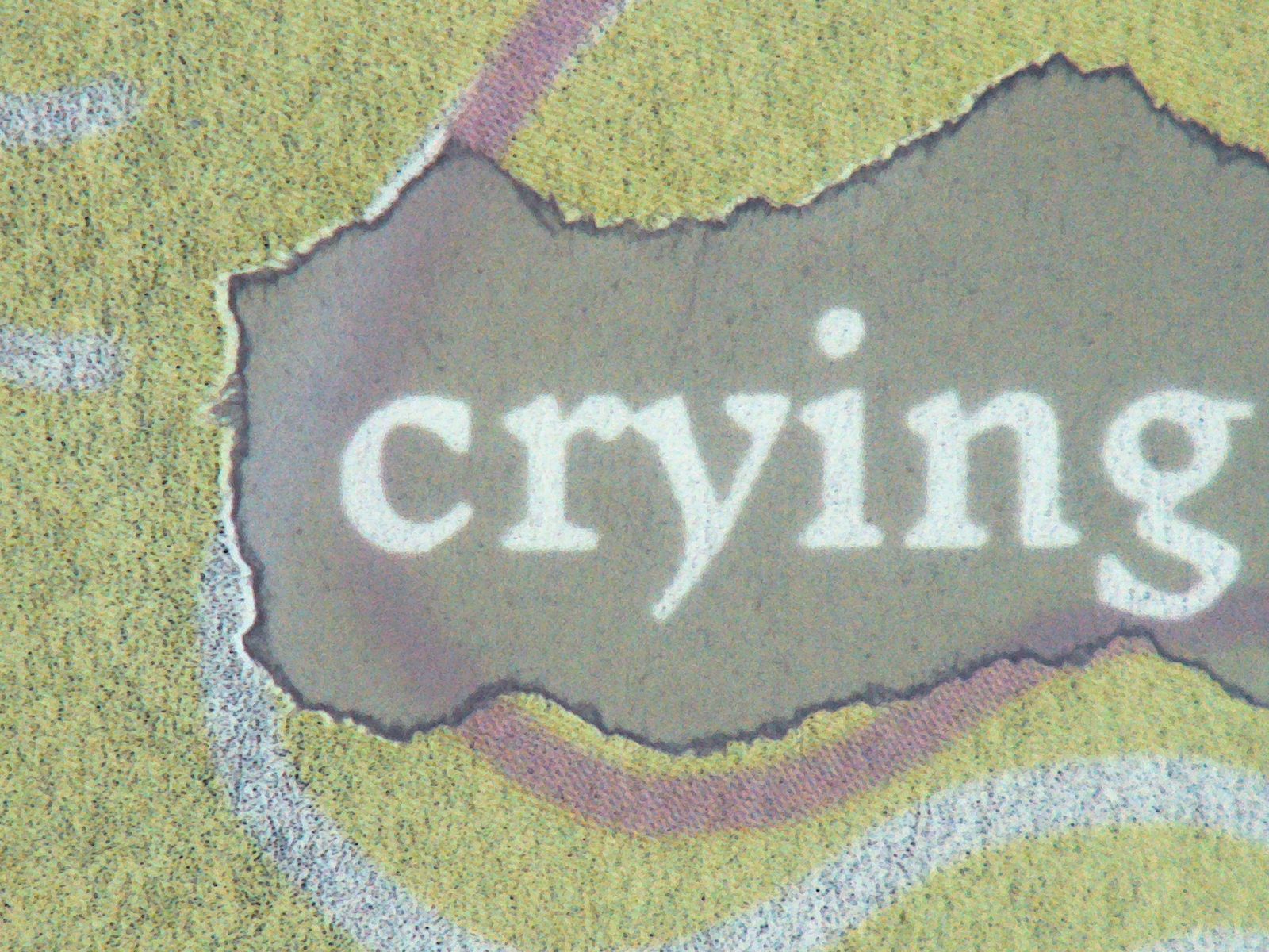 Torn paper fragment reading crying on a red and green page