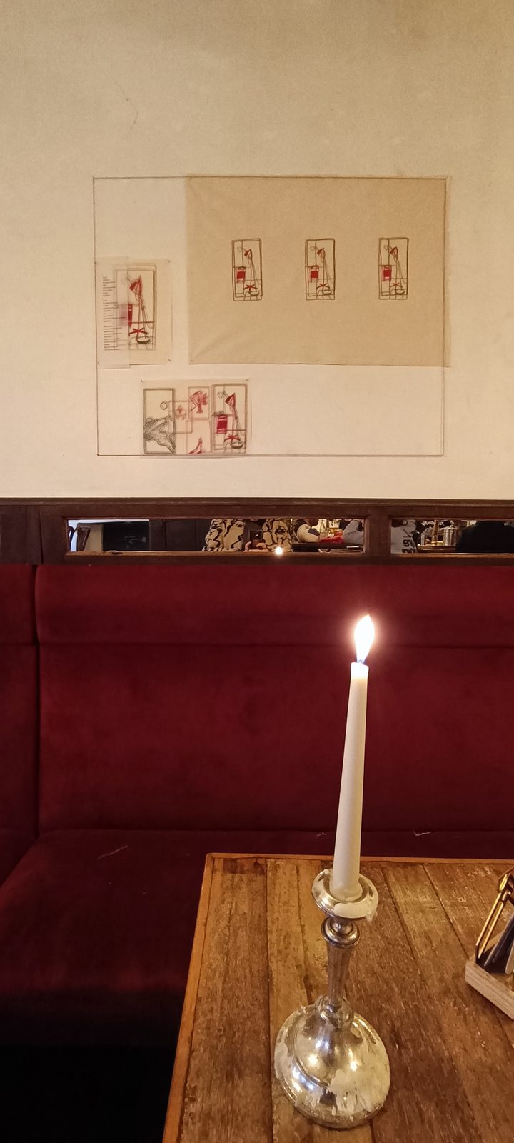 Lit candle on a table in front of the exhibition wall