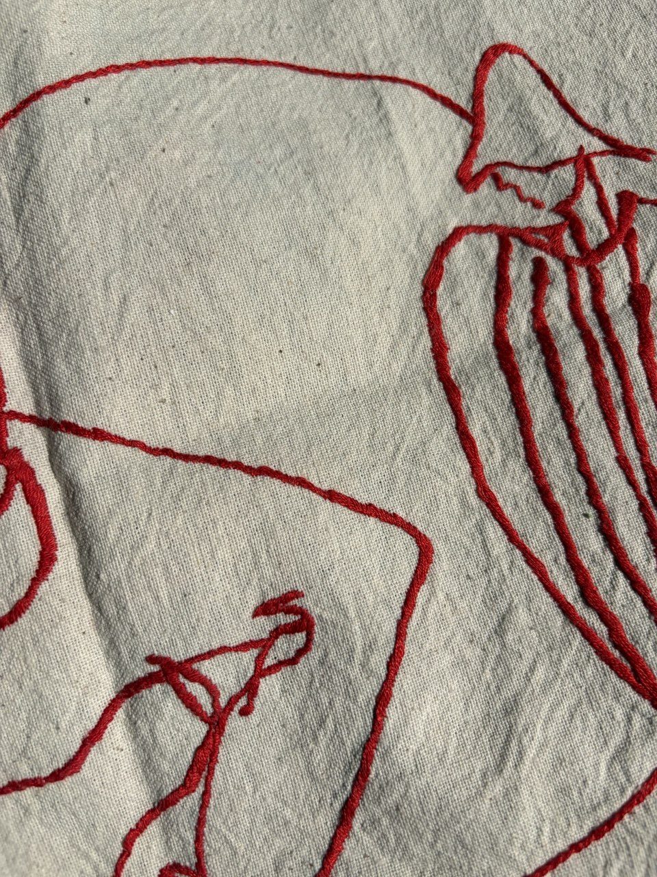 Detail of dense red-thread embroidery forming a robed figure