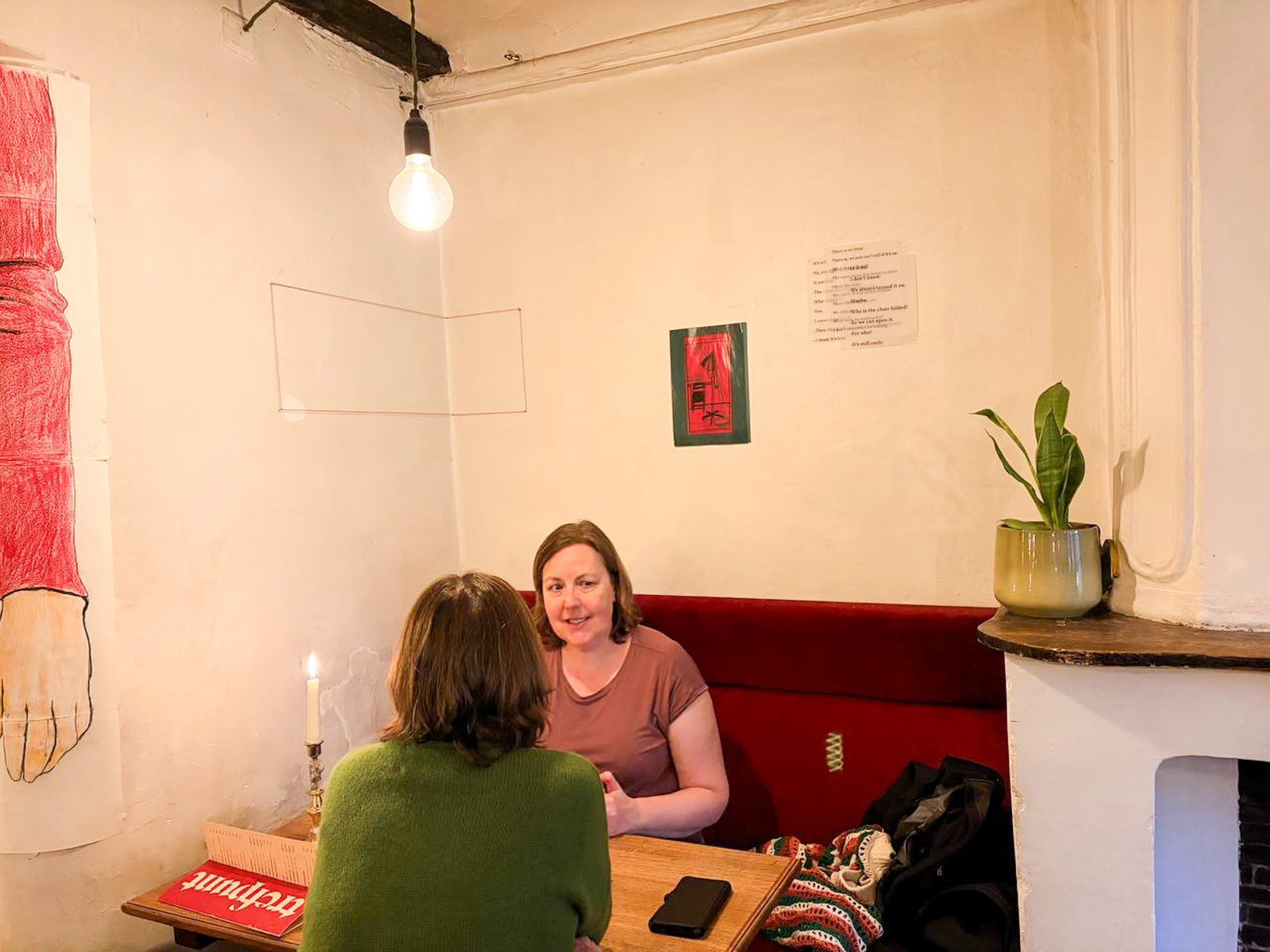 Visitor seated by the fireplace beneath a small red work