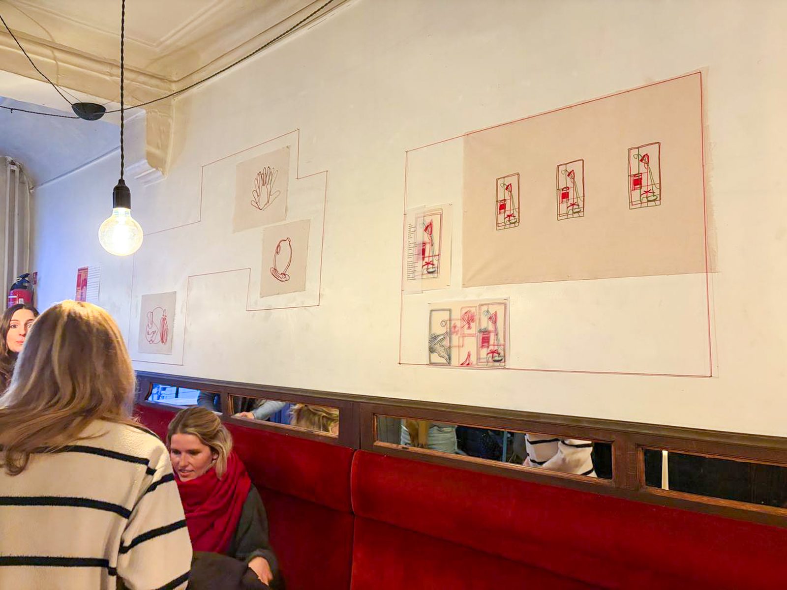 Visitors looking at small framed drawings in the exhibition