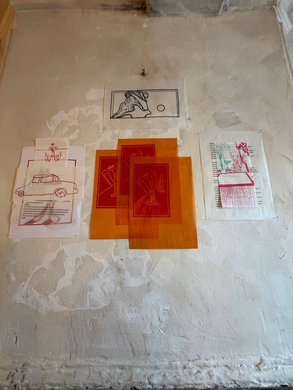 Cluster of prints and orange overlays with a drawing pinned above